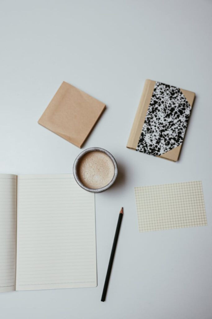 Photo by Cup of Couple Aerial view of notepads, pencil, and coffee on a minimalist desktop.